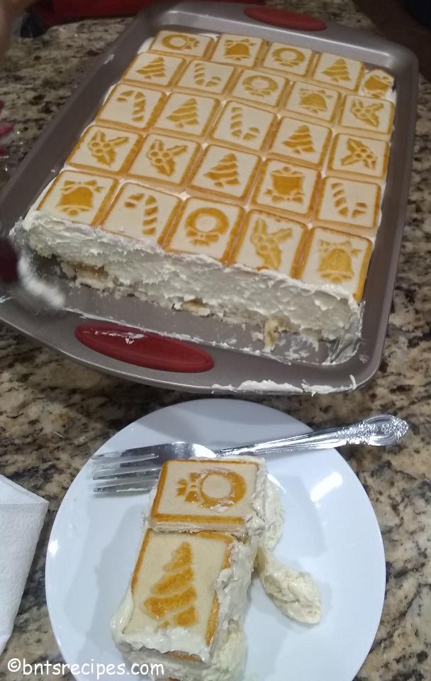 chessmen cookies banana pudding in a baking dish and sliced on a white plate with a fork on top of a granite countertop