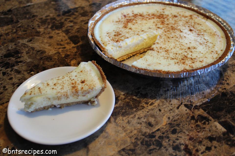 whole pie and slice of classic cheesecake with cinnamon dusting