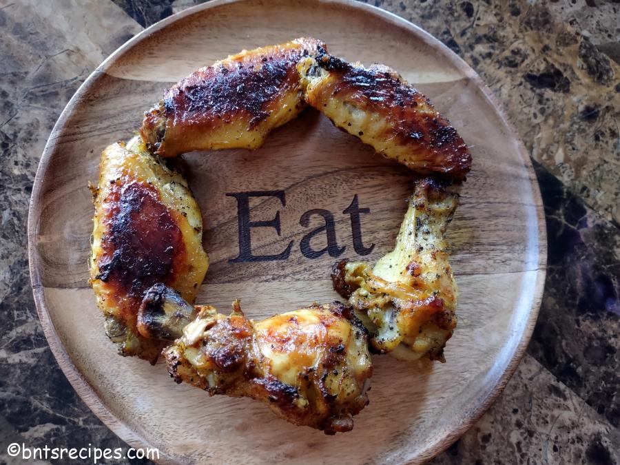 aerial view of sweet chili baked chicken wings on a wooden plate that says Eat on it