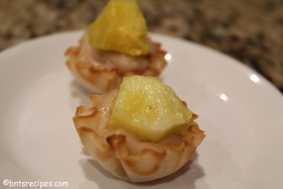 close-up of tropical phyllo shells with pineapple chunk topping on white plate