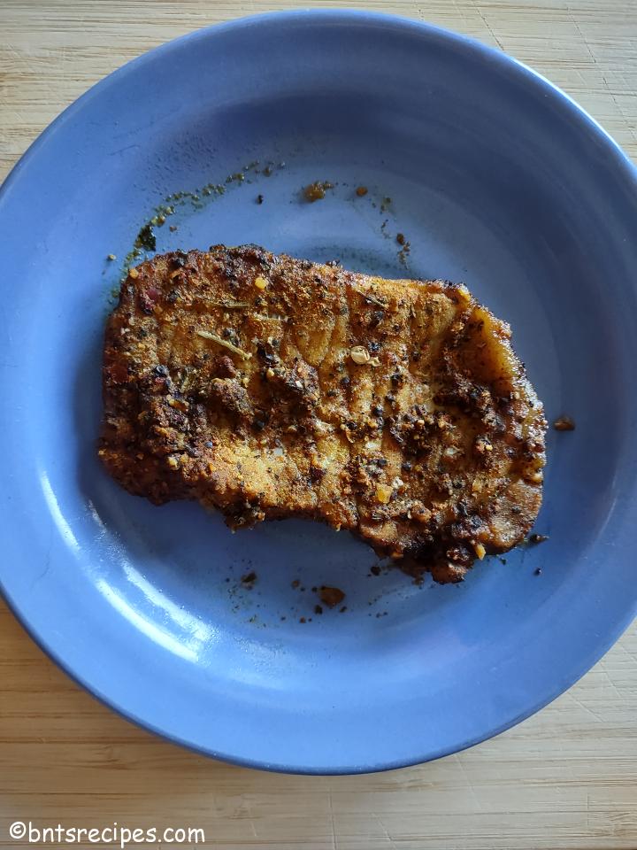 aerial view of baked berbere-spiced boneless pork chop on blue plate