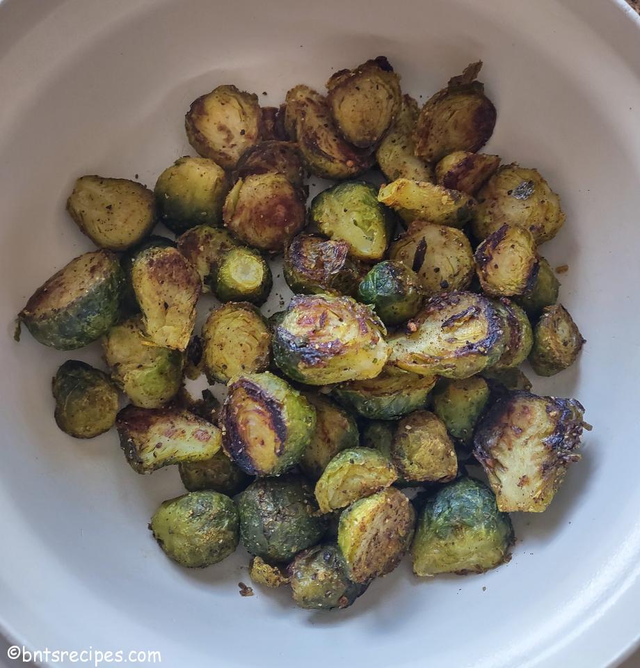 roasted brussels sprouts with a little char on them in a cream colored bowl