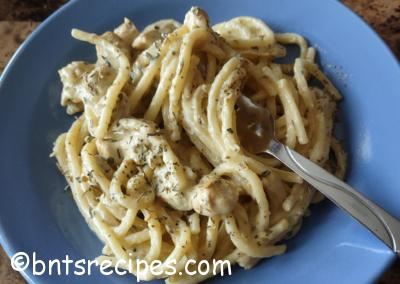 close-up of cajun chicken alfredo on a blue plate with a silver fork atop a granite counter