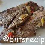 close-up of juicy and tender steak cooked in a crockpot on a white plate with bell peppers
