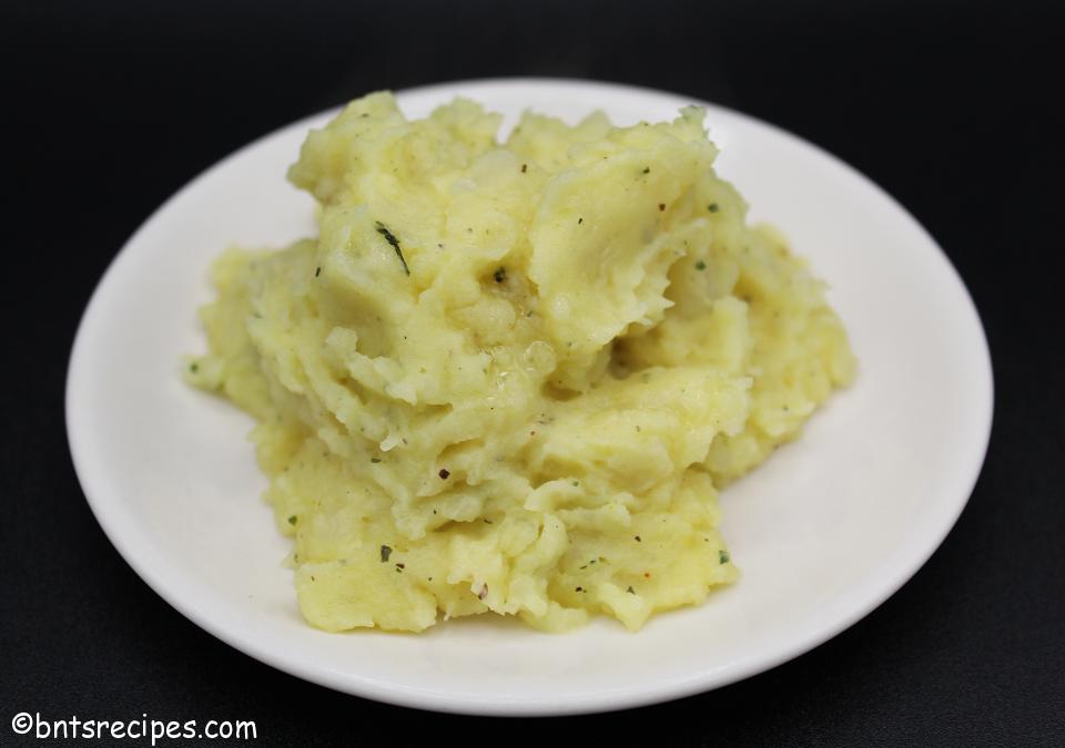 creamy buttery mashed potatoes from scratch on a white plate with black background