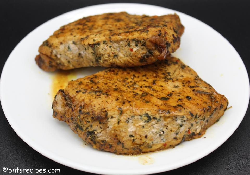 close-up of thick cut saucy seared and baked boneless pork chops on a white plate