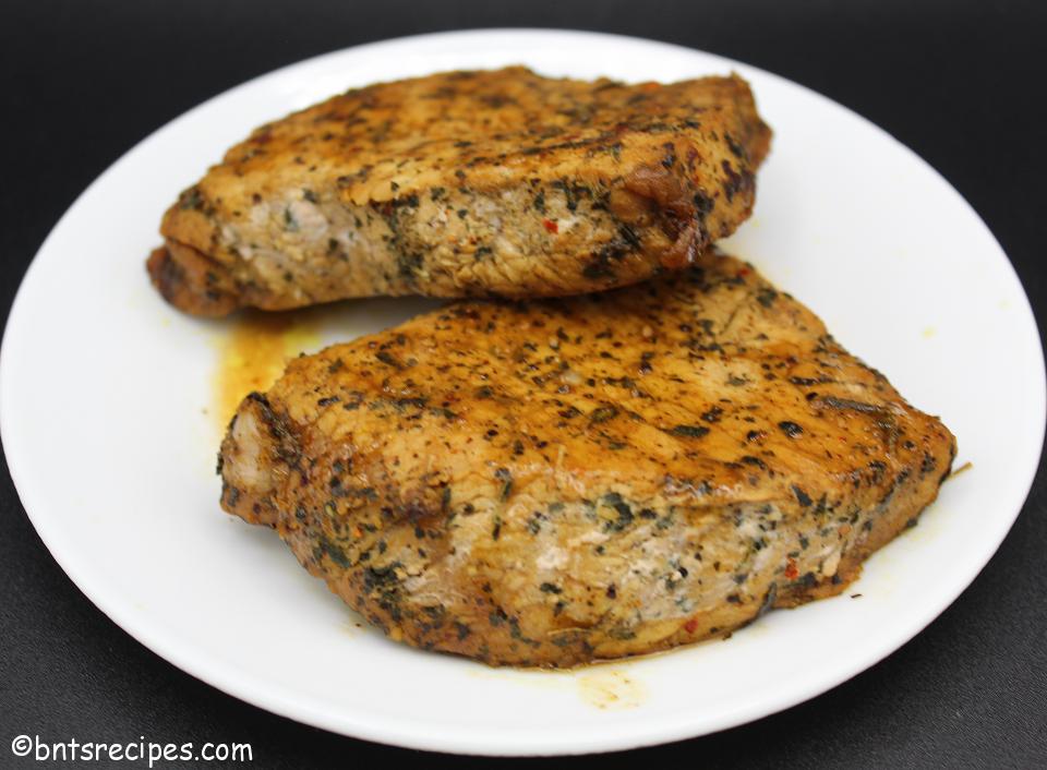 close-up of thick cut saucy seared and baked boneless pork chops on a white plate