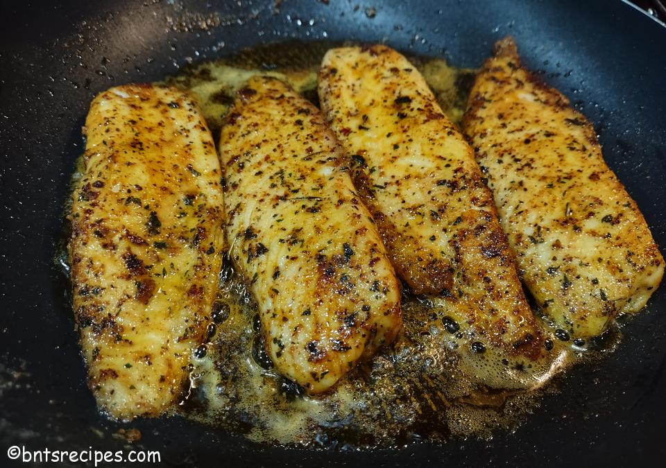 front view of no-shell taco-flavored tilapia searing in a pan with butter and oil