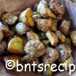 a wooden bowl of roasted red baby potatoes with herbs and spices