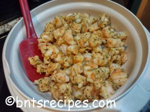 diced sauteed shrimp with red spatula in cream colored bowl