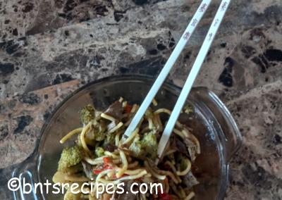 bowl of steak stir fry with vegetables and noodles with chopsticks