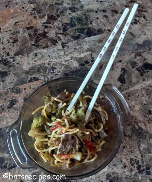 bowl of steak stir fry with vegetables and noodles with chopsticks