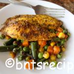 roasted tilapia and mixed vegetables on white plate with fork on granite counter
