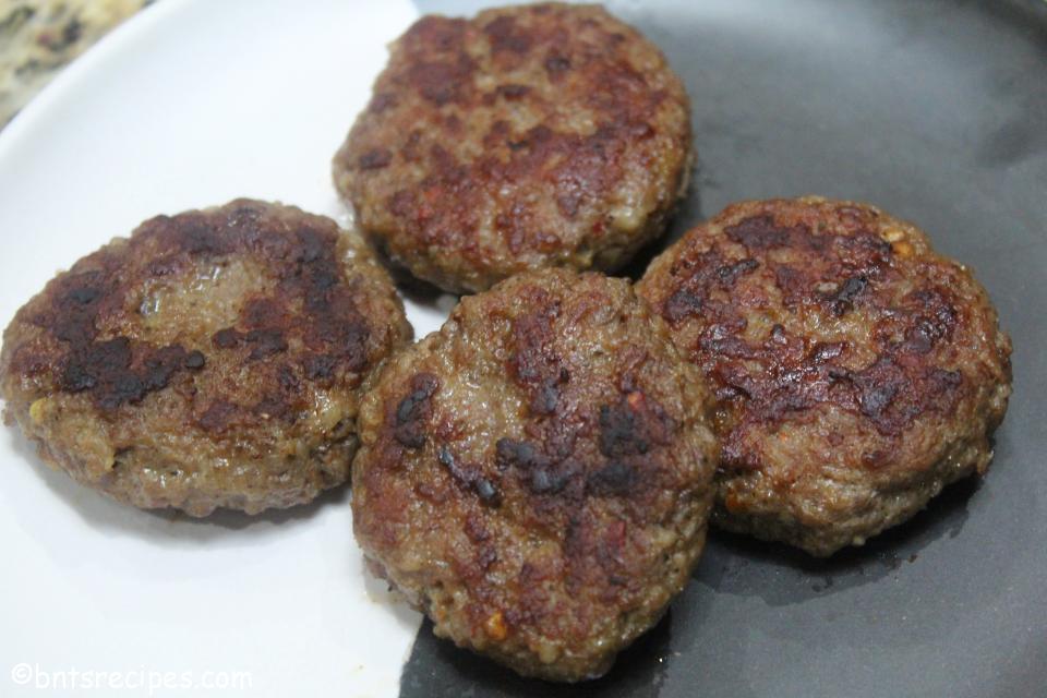 close-up of cooked breakfast sausage patties on black white abstract bamboo plate
