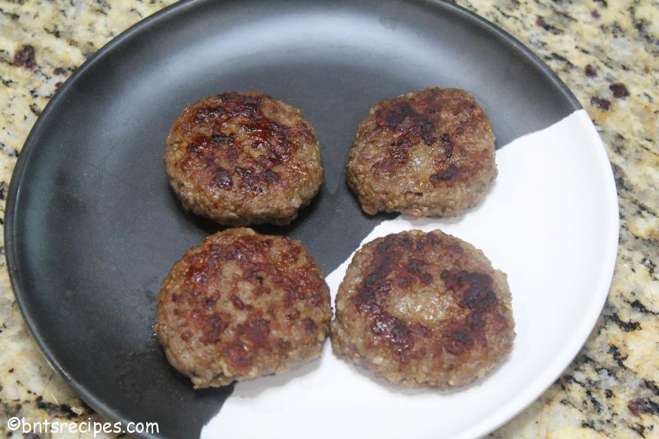 aerial view of cooked breakfast sausage patties on black white abstract bamboo plate
