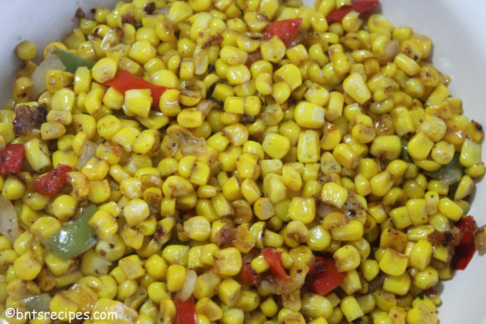 close-up of pan-fried corn with peppers and onions in beige bowl