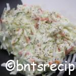 aerial view of creamy coleslaw with pepper garnished on top in a white and black abstract bamboo bowl