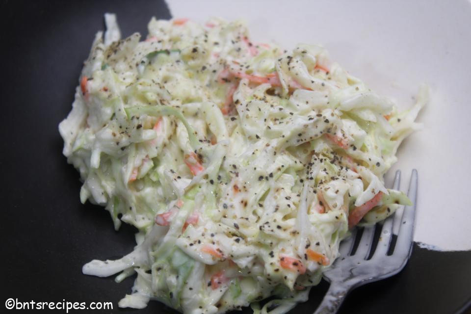 aerial view of creamy coleslaw with pepper garnished on top in a white and black abstract bamboo bowl