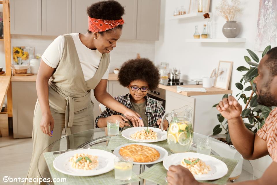 family eating dinner together; mother serving plate to child while father looks on