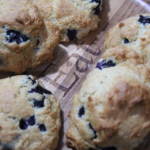close up of blueberry filled drop scones on wooden plate that says 'EAT'