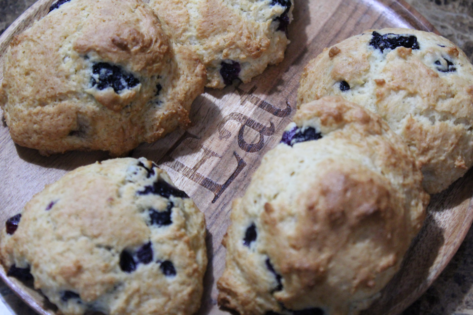 close up of blueberry filled drop scones on wooden plate that says 'EAT'